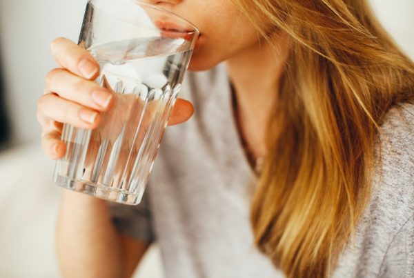 women in gray shirt drinking a large glass of water