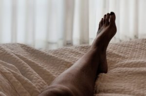leg in bed with beige blanket