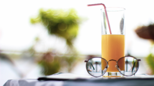 glass of orange juice on a table with a pair of glasses