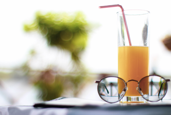 glass of orange juice on a table with a pair of glasses